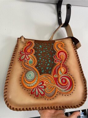 Artisan structured leather handbag features intricate floral embroidery